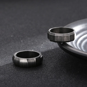 Macro detail of dark grey brushed titanium steel ring with industrial geometric facets