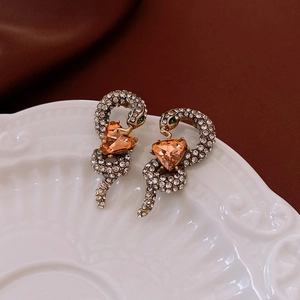 Detailed shot of vintage gold snake earrings with orange gemstones and crystals