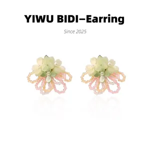 Close-up of handmade floral earrings with matte green petals and crystal beaded tassels