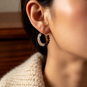 Close-up of vintage tiger eye and zircon hoop earrings worn with a cozy knit sweater