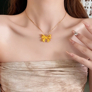 Macro view of detailed 18K gold bow pendant necklace on model neck with fine engraving