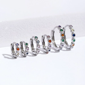 Detail of silver huggie hoop earrings with colorful gemstones in six graduated sizes
