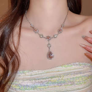 Dettaglio della collana con ciondolo in cristallo rosa a forma di pera indossata da una modella