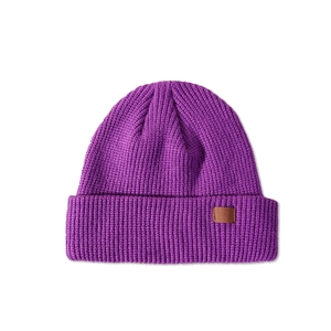 Detailed close-up of purple knit beanie texture with a brown leather decorative label