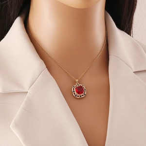 Detail of a vintage gold necklace with a red square gemstone pendant on a female model