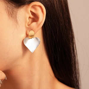 Detail of mixed-metal heart earrings with gold plating and silver brushed texture