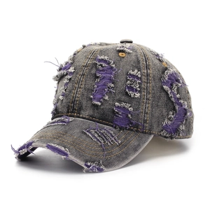 Detailed macro view of distressed denim fabric with purple frayed patches and yellow stitching