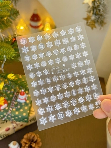 Detailed view of white snowflake nail stickers featuring 3D embossed holiday patterns