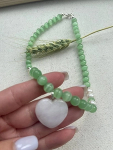 Detail of glacier blue cat eye beads and heart pendant on a beaded collar necklace