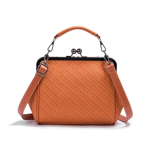 Macro shot of orange woven texture handbag with metal frame and ball clasp closure