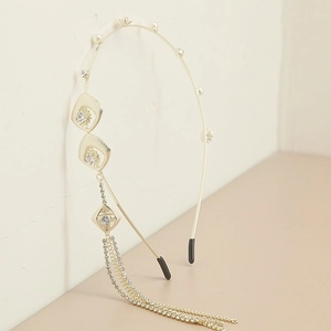 Detail of gold diamond headband with pearl accents and long rhinestone tassel charms