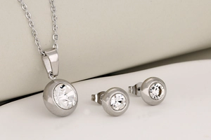 Close-up of silver-toned stainless steel jewelry set featuring round cut clear crystals
