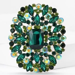 Macro shot of gold alloy brooch with faceted green and yellow crystals on white surface