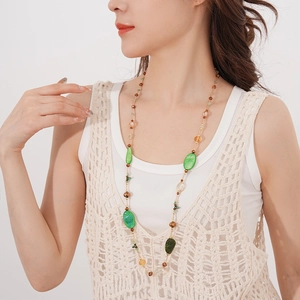 Detail of long bohemian necklace with green agate beads and vintage gold accents on model