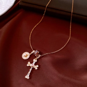 Macro view of 18k gold plated cross and starburst pendants on silk background