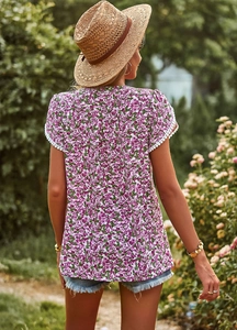 Detail of white short sleeve top with purple floral print and elegant white lace trim