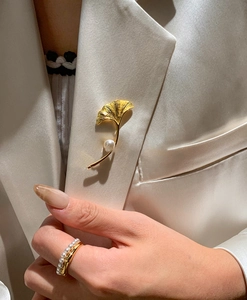 Dettaglio ravvicinato della spilla a foglia di ginkgo placcata oro 18K con perla bianca