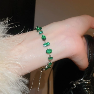 Detail of emerald zircon bracelet featuring drop and oval cut gemstones on a silver chain
