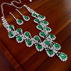 Détail du parure collier et boucles d'oreilles émeraude de luxe sur fond bois sombre