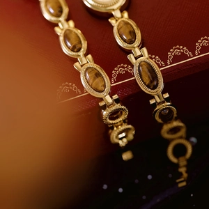Detail of vintage gold tiger eye stone watch strap displayed on a red luxury gift box