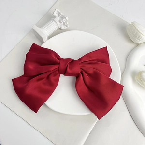 Detailed view of a large red satin bow hair clip on an elegant white decorative tray