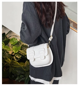 Detailed close-up of white PU leather saddle bag featuring unique double buckle design