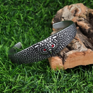 Gothic owl cuff bracelet in stainless steel with detailed feather texture and red eyes