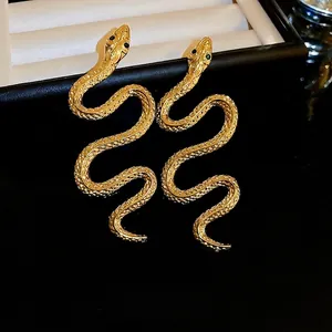 Exquisite gold snake drop earrings with sparkling green eyes and scale texture