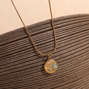 Macro view of 18K gold plated celestial compass pendant with stars and moon engravings