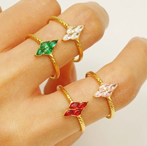 Close-up of four adjustable gold rings featuring white green red and pink marquise stones