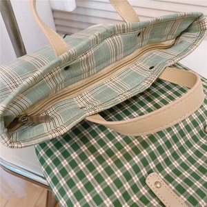 Close-up of metal zipper closure and interior space of green plaid canvas tote bag