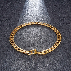 Macro detail of 18K gold plated Cuban link chain bracelet with polished lobster clasp