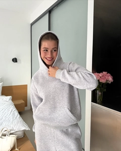 Close-up of grey hooded tracksuit set with drawstring pants on a model in a cozy room