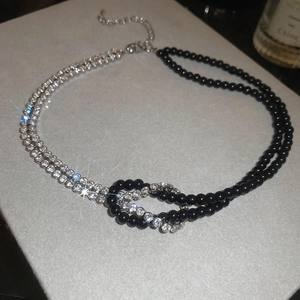 Dettaglio della collana Y2K con perline nere, catena di cristalli e design a nodo