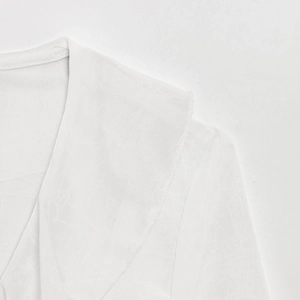 Detailed close-up of V-neckline and shoulder stitching on a white linen shirt