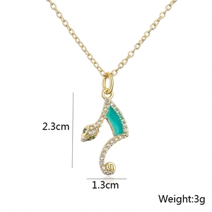 Detailed view of gold snake pendant with green zircon eyes and clear stones, 2.3cm high