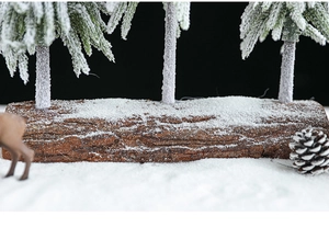 Macro detail of miniature Christmas trees with artificial snow on natural bark base