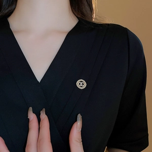 Close-up of gold-plated flower brooch with white zircons on a black elegant top