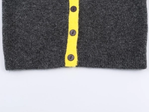 Detail of dark grey chunky knit cardigan featuring neon yellow trim and dark round buttons