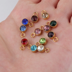Close-up of assorted 6mm colorful birthstone pendants in gold finish on a hand