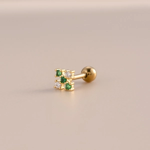 Macro detail of golden stud earring featuring green zircon stones and screw ball closure