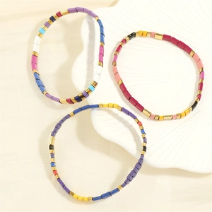 Detail of three colorful Tila enamel bead bracelets with golden spacers on shell