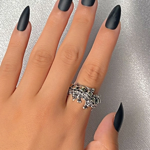 Dettaglio macro di anelli teschio punk retrò indossati con unghie a stiletto nere opache