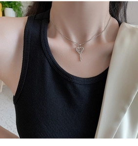 Gros plan d'un collier clé en forme de cœur argenté avec cristaux porté par un mannequin