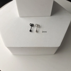 Détail de boucles d'oreilles boules de 3mm en noir et argent sur plateau blanc