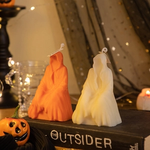 Detail of Halloween ghost candles in orange and white on a book with festive decor