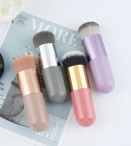 Detail of four colorful portable foundation brushes with dense bristles on magazine