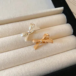 Mini metallic bow hair clips in polished gold and silver finishes on a jewelry tray