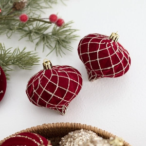 Boules de Noël en velours rouge foncé avec filet pailleté doré sur branches de sapin