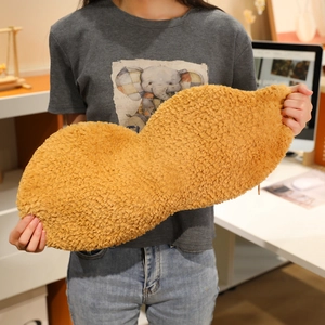 Close-up of a large peanut-shaped plush pillow featuring soft camel faux fur texture